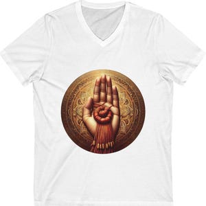 May include: White V-neck t-shirt featuring a detailed illustration of a hand with a red and gold design. The hand is centered within a golden circular pattern with intricate details, creating a spiritual or artistic theme.