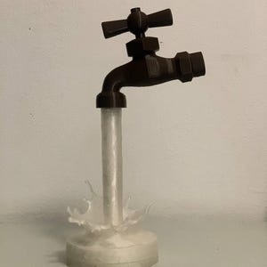 Könnte beinhalten: Eine dekorative Skulptur eines Wasserhahns mit braunem Finish, der Wasser zu gießen scheint. Der Wasserstrahl ist klar, mit einem Spritzeffekt an der Basis. Der Wasserhahn ist auf einem runden, weißen Sockel montiert.