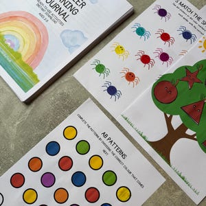 Könnte beinhalten: Ein Lernjournal für Kleinkinder mit Regenbogen-Cover und 50 fertigen Aktivitäten für 2- bis 5-Jährige. Enthalten sind Arbeitsblätter mit bunten Spinnen, einem Baum mit Fruchtformen und einem AB-Muster-Arbeitsblatt mit Kreisen.