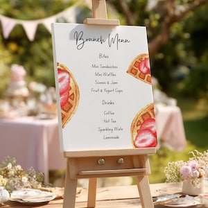 May include: A wooden easel displays a brunch menu with the title "Brunch Menu" in elegant script. The menu lists various food and drink options, with watercolor illustrations of waffles and strawberries.