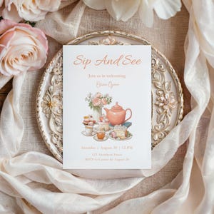 Könnte beinhalten: Eine weiße Einladungskarte mit dem Text "Sip And See" und Veranstaltungsdetails, mit einer Aquarellillustration einer Teekanne, Kuchen und Teetassen. Die Karte liegt auf einem dekorativen, verzierten Teller, umgeben von Blumen und Stoff.
