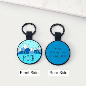 May include: Two-sided pet ID tag. The front side features a mountain scene with the name "MOCHI". The rear side is blue with the text "I'm lost Call my mom 914-922-8511". The tag has a black ring for attachment.