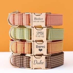 May include: A stack of four personalized dog collars with gold-colored buckles. The collars are in various colors and patterns, including red, green, yellow, and brown gingham. Each buckle has a dog's name and a phone number or message.