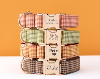 May include: A stack of four personalized dog collars with gold-colored buckles. The collars are in various colors and patterns, including red, green, yellow, and brown gingham. Each buckle has a dog's name and a phone number or message.