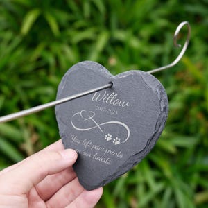 May include: A heart-shaped, dark gray slate memorial stake with the name "Willow" and dates 2017-2025 engraved in white. The stake features an infinity symbol and paw prints, with the text "You left paw prints on our hearts."