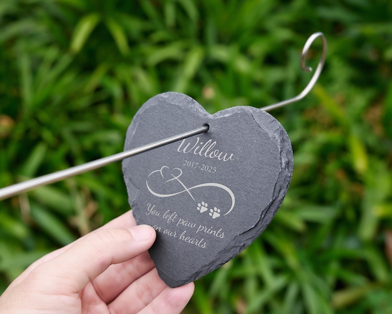 May include: A heart-shaped, dark gray slate memorial stake with the name "Willow" and dates 2017-2025 engraved in white. The stake features an infinity symbol and paw prints, with the text "You left paw prints on our hearts."