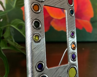 May include: Silver metal light switch cover with a decorative border of colorful circles. The circles are in shades of purple, orange, yellow, green, and blue.