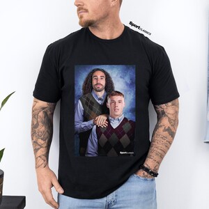 May include: Black t-shirt featuring a portrait of two men wearing argyle vests over collared shirts. The image has a blue background and the text "SportClassics" is visible.