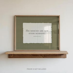May include: A rectangular wall art print featuring a dark olive green and white plaid background with a central off-white torn-edge paper overlay. The text reads: His mercies are new every morning. Lamentations 3:22-23. The print is displayed in a wooden frame.