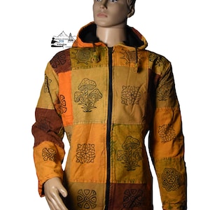 Puede incluir: Chaqueta con capucha de patchwork en tonos tierra, con diseños negros de setas y flores en cada cuadrado. La chaqueta tiene una cremallera completa y se muestra en un maniquí.