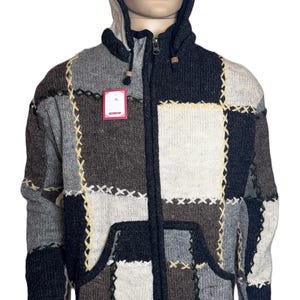 Puede incluir: Una sudadera con capucha y cremallera completa que presenta un diseño de parches en tonos negro, gris, marrón y crema. Los paneles de punto están unidos por costuras cruzadas visibles en amarillo y negro. Incluye cremallera y dos bolsillos.