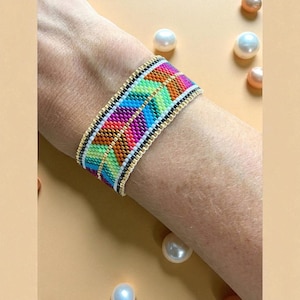 May include: A colorful beaded bracelet with a chevron pattern. The bracelet features a vibrant mix of colors including pink, orange, green, and blue. The edges are trimmed with gold and black beads, creating a striking contrast. This accessory is a bold statement piece.