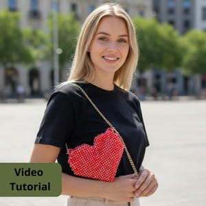 May include: A red beaded heart-shaped purse with a gold chain strap. The purse is made of small red beads and has a textured surface. The words "Video Tutorial" are in a green rectangle.
