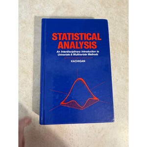 May include: A blue hardcover textbook titled Statistical Analysis: An Interdisciplinary Introduction to Univariate & Multivariate Methods by Kachigan. The cover features bold orange text and a geometric bell curve graphic in orange lines.