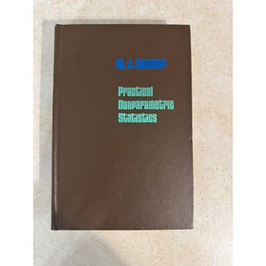 May include: A brown hardcover book titled Practical Nonparametric Statistics with the author name W. J. Conover printed in blue. The title is printed in a light teal color on the front cover. The book has a solid brown textured cover.