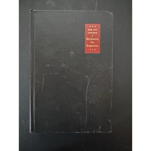 Könnte beinhalten: Ein schwarzes Hardcover-Buch mit einem roten Etikett. Das Etikett trägt die Aufschrift "BEER AND JOHNSTON" über "Mechanics for Engineers". Das Buch weist Gebrauchsspuren auf.
