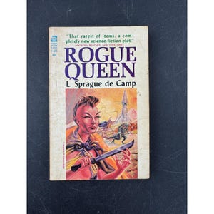 May include: A vintage paperback book titled Rogue Queen by L. Sprague de Camp. The cover features a science fiction illustration of a person with a mohawk holding a blade, with a rocket ship in the background. The text includes the Ace Science Fiction Classic logo and the price of 40 cents.