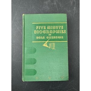 May include: A green hardcover book titled "Five Minute Biographies" by Dale Carnegie. The book cover features gold lettering and a gold graphic. The book is closed and in good condition.