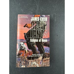 May include: A paperback book titled "Deathlands: Eclipse at Noon" by James Axler. The cover features a man with a gun, a dog, and the text "Blazing a perilous trail through the heart of darkness."