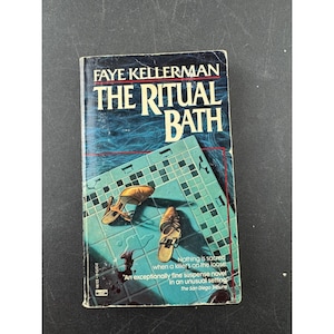 May include: A paperback book titled "THE RITUAL BATH" by Faye Kellerman. The cover features a teal tile pattern with a pair of women's shoes and text that reads "Nothing is sacred when a killer's on the loose."