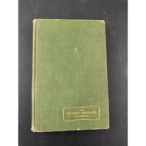 May include: A vintage book with a green cover. The cover has a textured appearance and a rectangular label with gold lettering that reads "THE WILLIAMS & WILKINS CO BALTIMORE". The book is closed and appears to be in good condition.