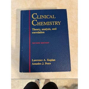 May include: A dark blue hardcover textbook titled Clinical Chemistry: Theory, analysis, and correlation, Second Edition, by Lawrence A. Kaplan and Amadeo J. Pesce. The cover features a textured finish with gold lettering and a vertical red line.