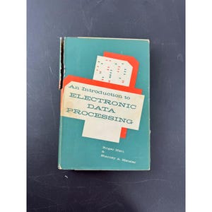 May include: A hardcover book titled An Introduction to Electronic Data Processing by Roger Nett and Stanley A. Hetzler. The teal cover features a white rectangular graphic with red accents and a pattern of small red and blue dashes.