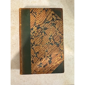 May include: An antique book with a brown and green cover. The cover features a marbled pattern in shades of brown, tan, and blue. The spine is green, and the edges of the pages are aged.