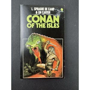 Könnte beinhalten: Ein Vintage-Taschenbuch mit dem Titel "CONAN OF THE ISLES" von L. Sprague de Camp & Lin Carter. Das Cover zeigt einen Krieger mit einem Schwert, der einer großen grünen und orangefarbenen Schlange gegenübersteht. Im Hintergrund sind Schädel zu sehen.
