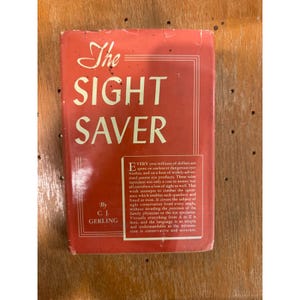May include: A vintage book titled "The Sight Saver" with a red cover and white lettering. The book's author is C.J. Gerling. The cover text includes a description of the book's purpose to combat eye quackery.