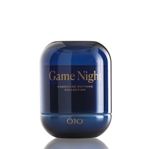 May include: A dark blue, rounded container with the words "Game Night" in gold lettering. The text "Masculine Rhythms Collection" is below the main text. The brand name "OJO" is at the bottom. The container has a glossy finish.