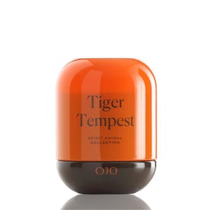 May include: A cylindrical product with a rounded top and base. The top is orange, and the base is dark brown. The text "Tiger Tempest" is printed on the orange section, with "Spirit Animal Collection" below. The brand name "OJO" is at the base.