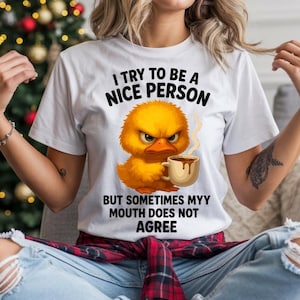 Peut inclure: T-shirt blanc avec le texte "I try to be a nice person but sometimes my mouth does not agree." Le t-shirt présente une image de dessin animé d'un canard jaune en colère tenant une tasse de café. Le t-shirt est porté par une personne.