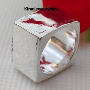 May include: A close-up of a silver ring with a rectangular design. The ring has a smooth, polished surface and a hollow interior. The text "Kiranjewellryhub" is visible in the image.