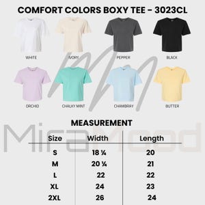 May include: A display of Comfort Colors Boxy Tee shirts in various colors, including white, ivory, pepper, and black. The image also shows shirts in orchid, chalky mint, chambray, and butter. Measurements are provided for sizes S through 2XL, with widths ranging from 18 1/4 to 26 inches.