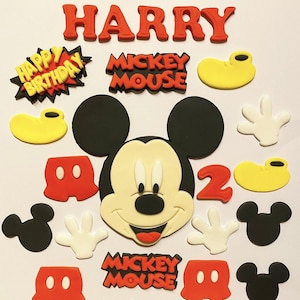 May include: A selection of colourful Mickey Mouse cake decorations. Includes the name "HARRY" in red, a "Happy Birthday" graphic, Mickey Mouse's face, hands, and shoes, and the number "2". The words "Mickey Mouse" are also present.