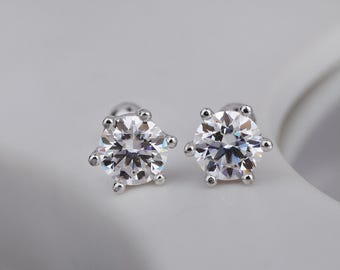 May include: A pair of stud earrings featuring large, round, clear gemstones. Each earring has a six-prong setting, with a small, round accent at the end of each prong. The earrings are set on a silver post.