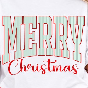 Könnte beinhalten: Ein weißes Kurzarm-T-Shirt mit dem Text MERRY in großen, hellgrün-weiß vertikal gestreiften Blockbuchstaben mit roter Umrandung und dem Wort Christmas in roter Schreibschrift, das unter dem Haupttext zentriert ist.