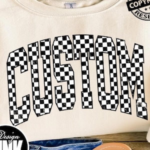 May include: A cream-colored crewneck sweatshirt featuring the word CUSTOM printed in a black and white checkered pattern across the chest. The text is arched in a collegiate font style. A circular black copyright badge is visible in the top right.