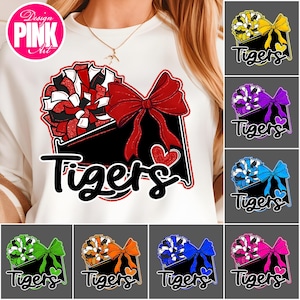 May include: White sweatshirt featuring a design with a red bow, pom-pom, and the word "Tigers" in black. The design includes a red heart and is surrounded by a black border. Additional designs with different color combinations are also shown.