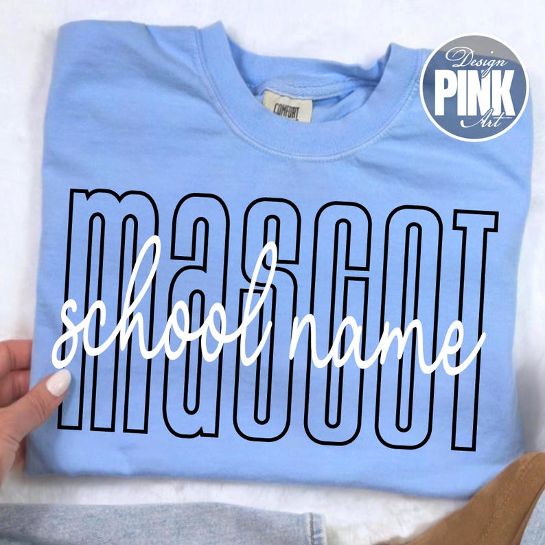 K&ouml;nnte beinhalten: Hellblaues Sweatshirt mit dem Wort "MASCOT" in fetter, schwarzer Blockschrift und den Worten "school name" in wei&szlig;er, kursiver Schrift. Das Sweatshirt hat einen Rundhalsausschnitt und ein "Comfort"-Etikett.