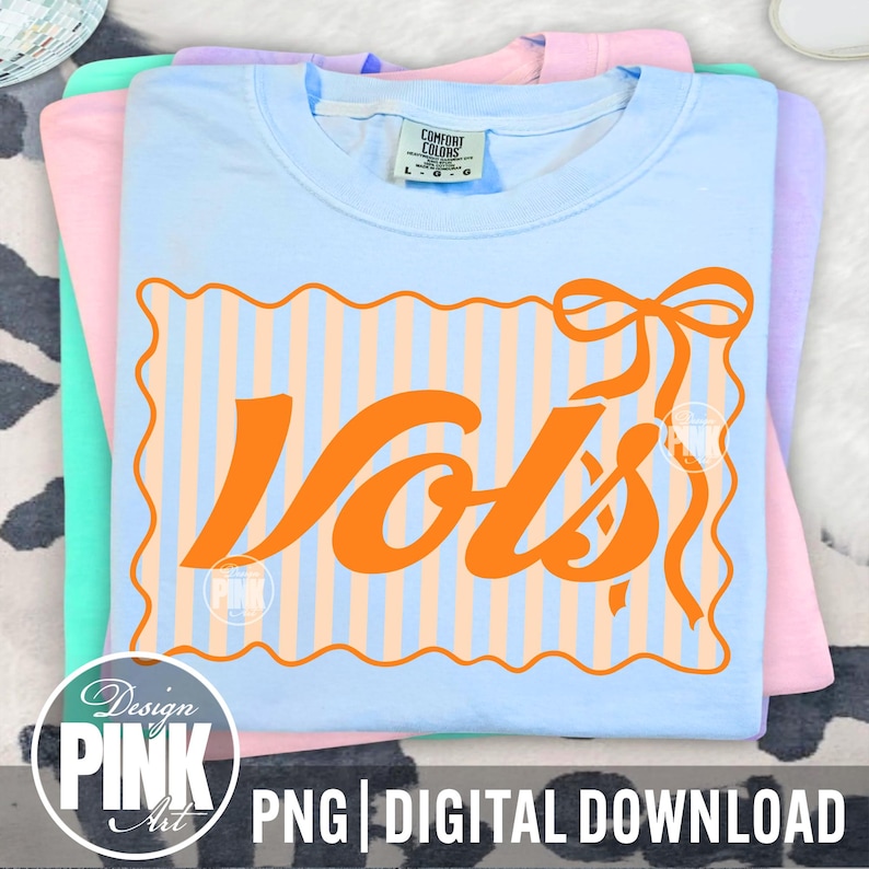 May include: A stack of pastel-colored t-shirts. The top shirt is light blue with an orange graphic that says "Vols" inside a striped frame with a bow. The shirts are labeled "Comfort Colors". The bottom of the image says "PNG | DIGITAL DOWNLOAD".