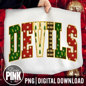 May include: White sweatshirt with the word "DEVILS" in a festive design. The letters are filled with patterns of Christmas trees, snowflakes, and knit textures in red, green, and cream colors. A "Design Pink Art" logo is in the bottom left.
