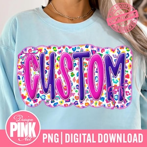 May include: Light blue sweatshirt with a large, colorful "CUSTOM" design. The word is in purple with a pink outline, set against a leopard print background. Pink bows accent the design. The bottom of the image reads "PNG | DIGITAL DOWNLOAD".