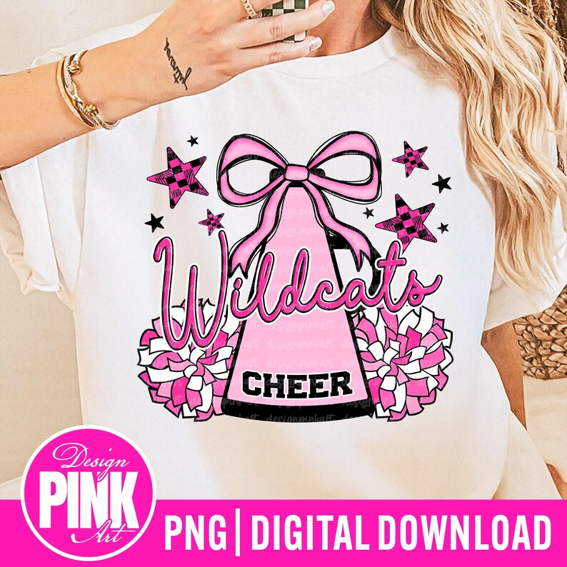 May include: White t-shirt featuring a pink and black design with the word "Wildcats" in a script font. The design includes a pink bow, stars, pom-poms, and the word "CHEER". The bottom of the image has the text "PNG DIGITAL DOWNLOAD".
