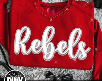 May include: A bright red long-sleeve sweatshirt featuring the word Rebels in a large, white, cursive font with a silver glitter outline. The garment has a crew neckline and a visible interior tag. The design is centered on the front of the shirt.