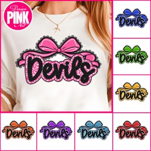 Op de afbeelding: Witte sweatshirt met een roze strik en het woord "Devils" in een zwart-roze ontwerp. Extra ontwerpen in blauw, groen, geel, oranje, paars en rood worden ook getoond.