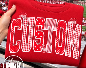 May include: A red crewneck sweatshirt featuring the word CUSTOM in large, block-style letters. Each letter has a unique white-outlined pattern, including red and white polka dots, gingham checks, and vertical stripes, set against a solid red fabric.