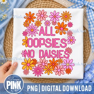 May include: A white t-shirt featuring the pink text ALL OOPSIES NO DAISIES centered on the front. The text is surrounded by a colorful border of illustrated flowers in shades of pink, light pink, and orange, arranged in a rectangular pattern.