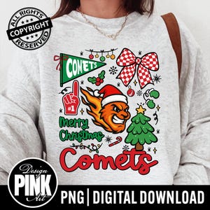 May include: A light gray sweatshirt with a colorful Christmas-themed graphic. The design includes a green pennant with "COMETS", a red and white checkered bow, a cartoon flame with a Santa hat, and a green Christmas tree. The words "Merry Christmas" and "Comets" are also featured.